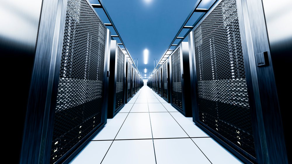 Long aisle of server racks with perforated metal doors under bright ceiling lights on a white tiled floor.