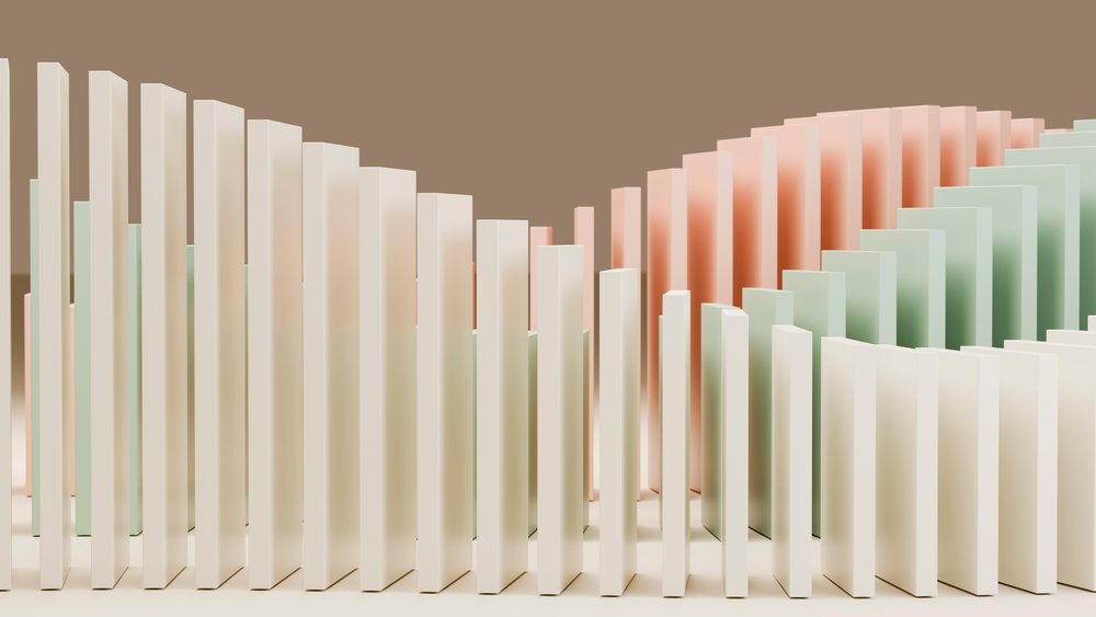 Multiple domino tiles in white, pink, and green arranged sequentially on a flat surface illustrating a falling chain reaction concept.