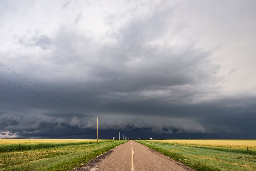 Storm Supercell clouds develop over a flat green field alongside highway 278 near Norton, HWY 278 Near Norton, New Mexico, USA.
