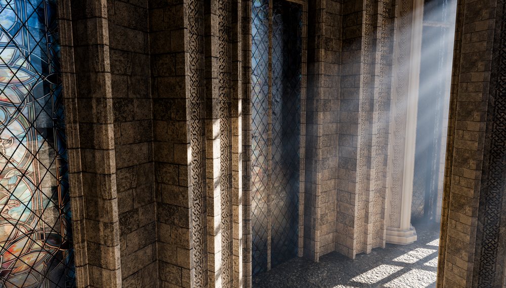 Sunlight rays illuminate stone walls, arched stained glass windows, and ornate carvings inside a medieval-style historic building corridor.