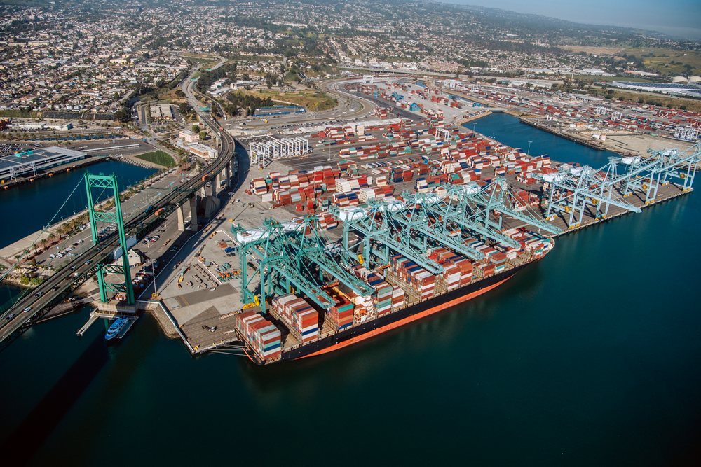 Container ship docked at the Port of Long Beach with cranes unloading shipping containers, CA, USA.