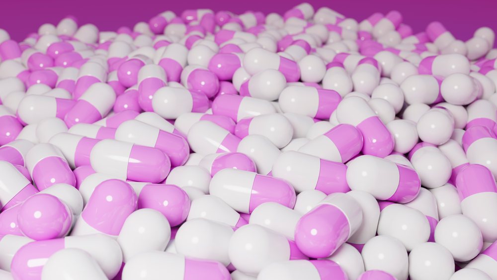 Glossy purple and white capsules filling the frame in a close-up pile.