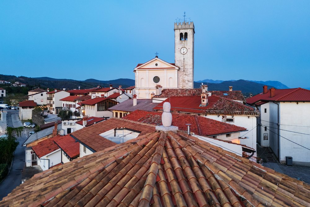 Church of St Martin with clock tower and red tile rooftops at dusk in the Vipava Valley, landscape, cityscape, Šmartno, Slovenia.