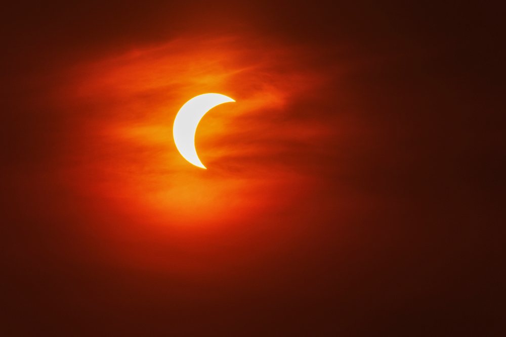 Partial solar eclipse with the sun partially obscured and glowing orange sky over, Landscape, Lifestyle, Valldemossa, Mallorca, Spain.