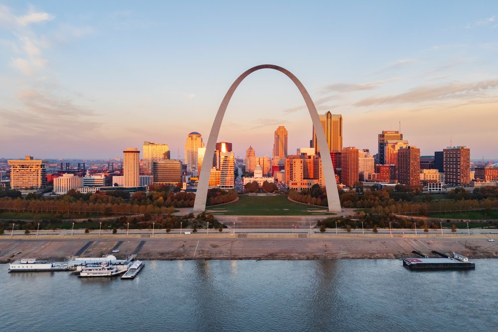 The Gateway Arch and St Louis skyline at sunrise feature an empty riverside promenade, riverfront, and urban park under a clear sky, Americana, Historic, Missouri, USA.