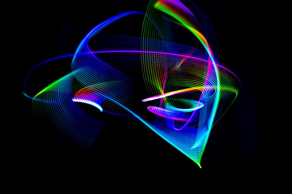 Colorful abstract light painting with swirling neon trails on a dark background creating dynamic patterns.