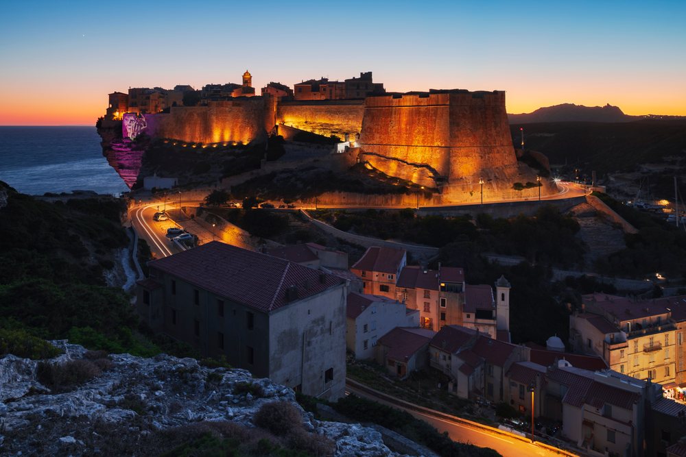 Illuminated citadel perched on a cliff overlooking the sea at Dusk, Travel Photography, Bonifacio, Corsica, France.