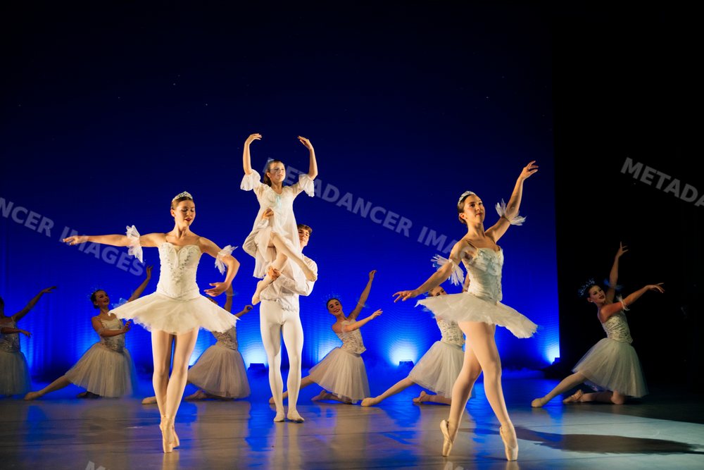Ballet dancers perform a classical lift and dance routine on stage