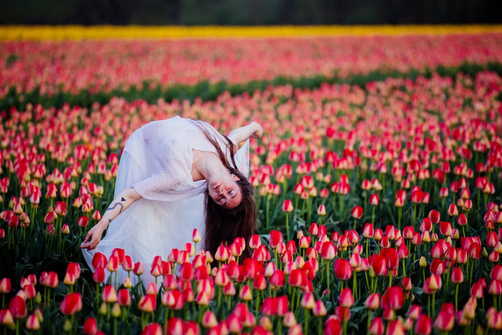 Woman dancing outdoors in a vibrant red tulip field during spring, USA.