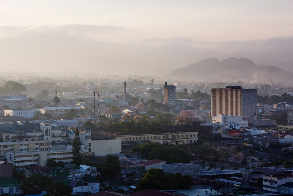 Panoramic cityscape of San Jose, showing fog over hills and mixed urban buildings under morning light, Costa Rica.