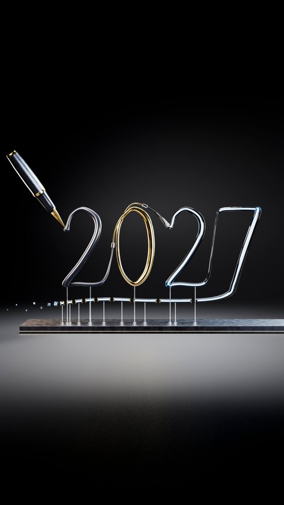 Metallic wire numbers forming 2027 with a pen writing the first digit on a reflective black base against a black background.