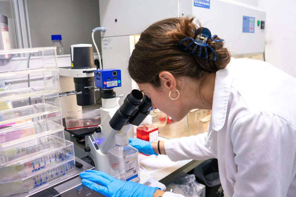 Woman in a Laboratory, examines samples using a microscope amid scientific equipment and sample containers, research, biology, Seville, Andalucía.