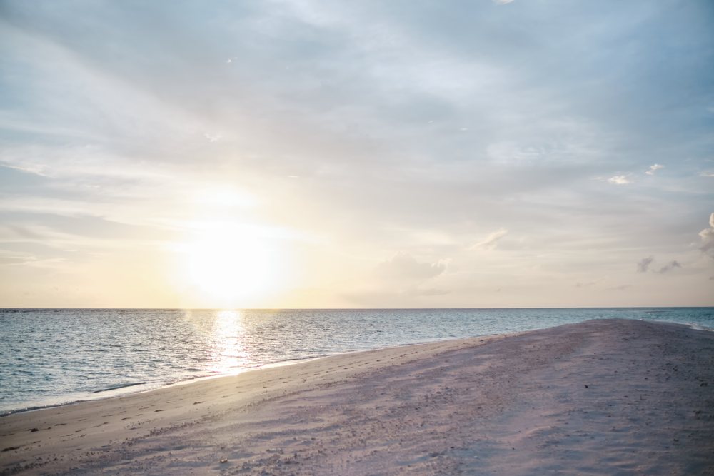 A serene sunset over a sandy beach and ocean shoreline in a beach