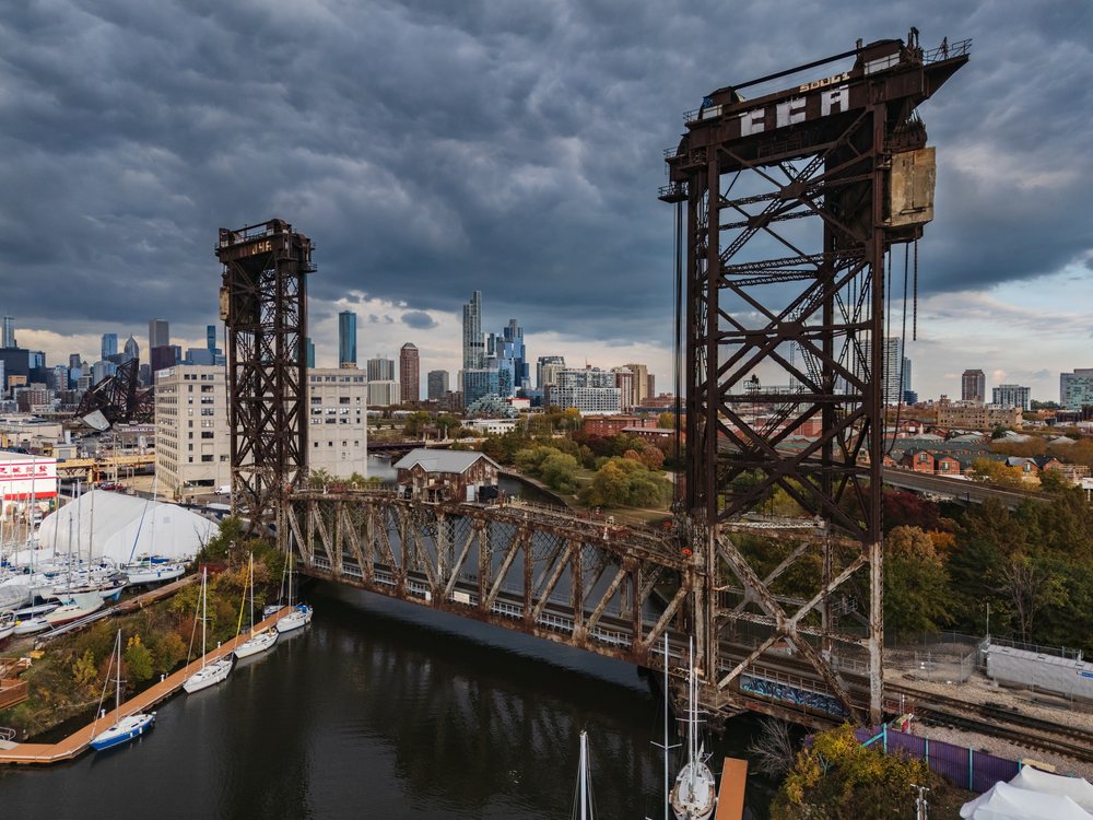 Canal Street Railway Bridge spans a river with boats docked nearby against the Chicago skyline under a cloudy sky, Americana, Historic, Illinois, USA.
