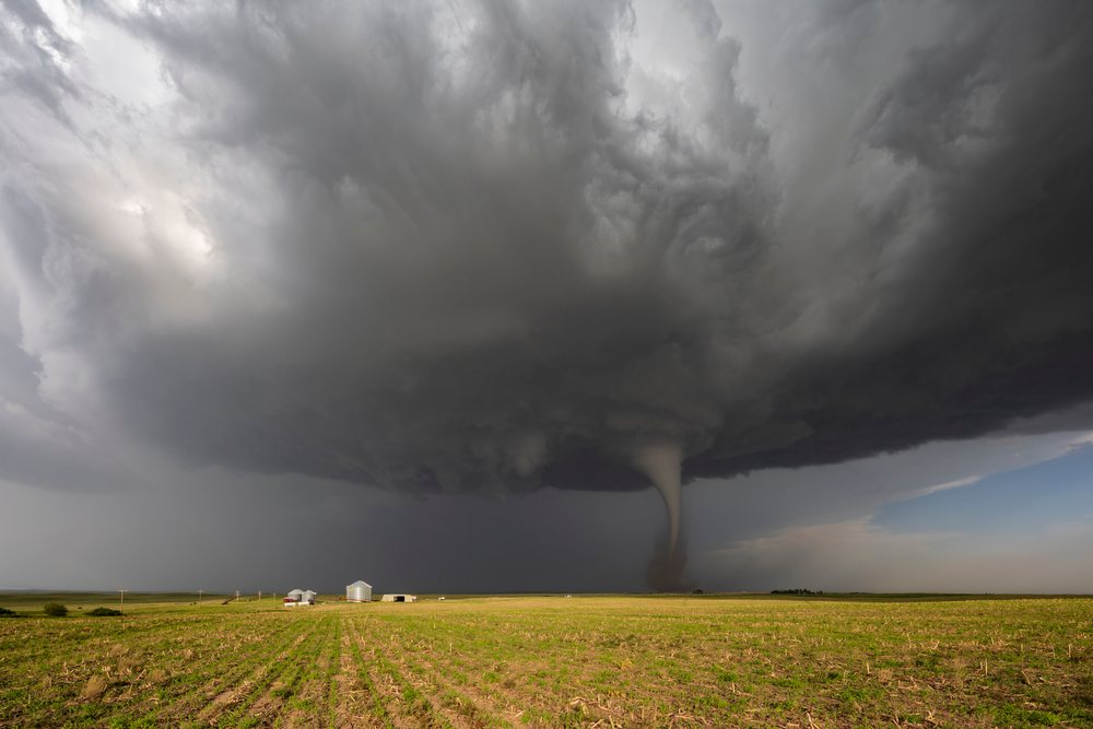 Tornado funnel forms beneath a dark supercell storm cloud over a rural field in Tornado Alley, Dickens, Nebraska, USA.