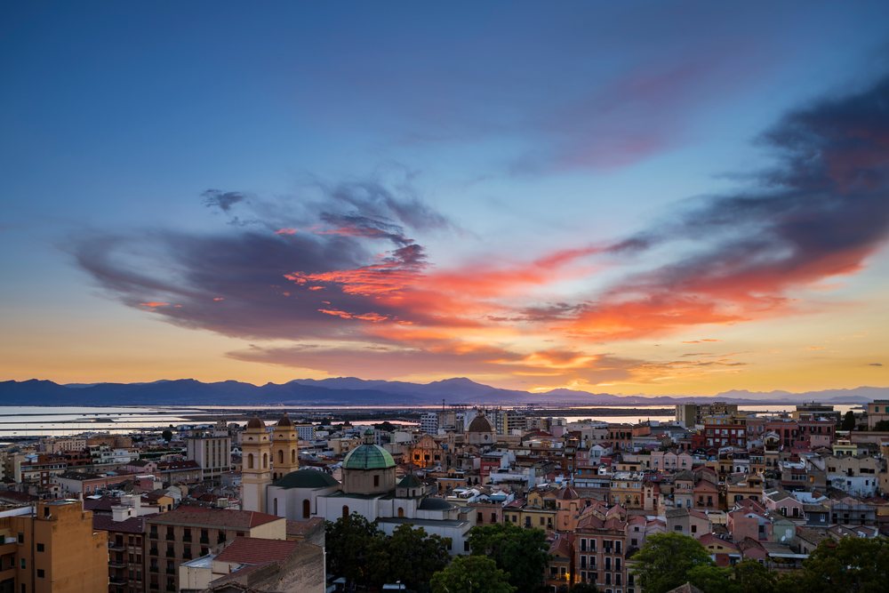 Cagliari city skyline at Sunset with colorful clouds, mountains, and nearby water, Travel Photography, Sardinia, Italy.