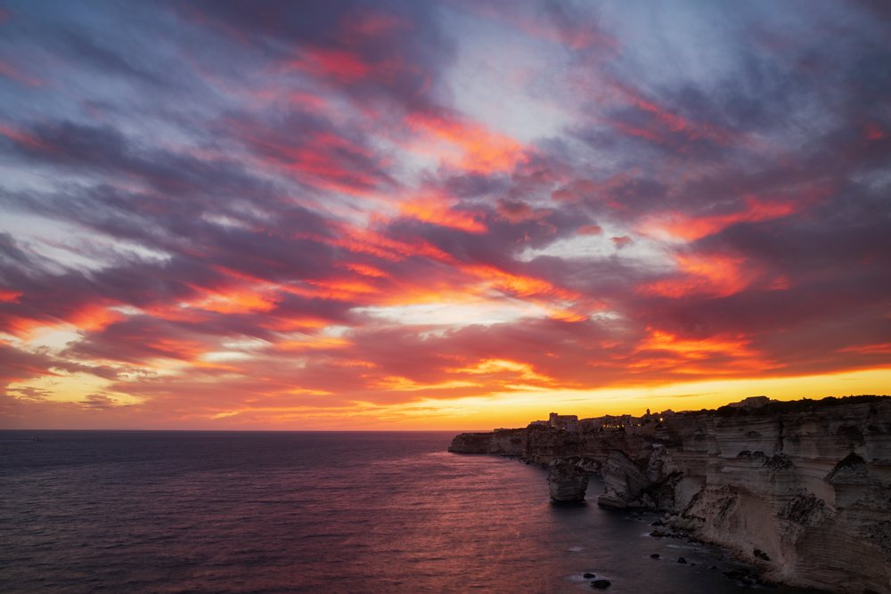 Sunset illuminates cliffs and sea, with colorful clouds above, Travel Photography, Bonifacio, Corsica, France.