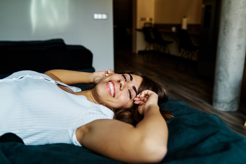 A woman is relaxing and smiling on a couch