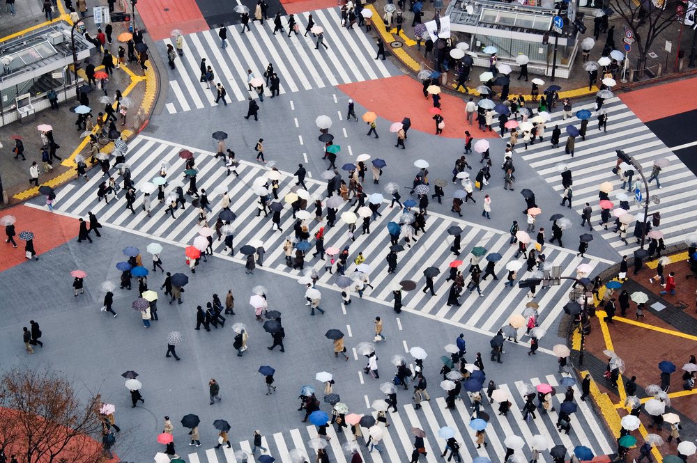 Aerial view of Shibuya Crossing showing many pedestrians holding umbrellas on a rainy day crossing the street, Tokyo, Japan.
