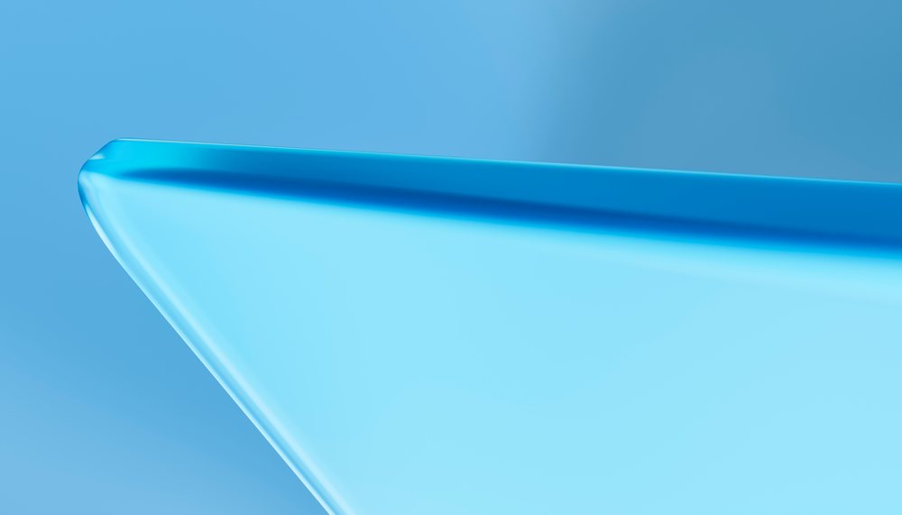 Close-up of a blue glass corner with smooth, rounded edges and a shiny transparent surface in a studio setting.