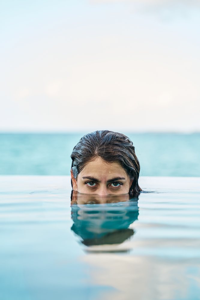 A white woman swims in an outdoor pool with calm water