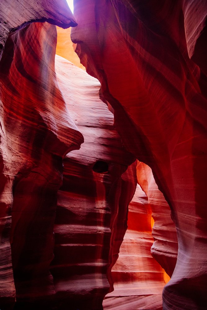 Sunlight illuminates the narrow red sandstone walls of Antelope Canyon slot canyon, Navajo Land, Arizona, USA.