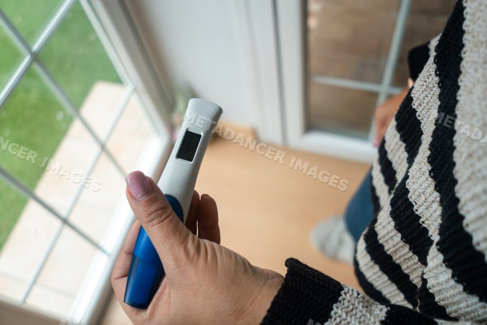 Woman reads pregnancy test result in her home by a window