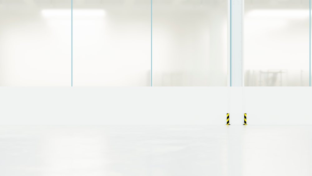 Empty car manufacturing factory floor with large windows, protective guards, and bright, clean industrial space.