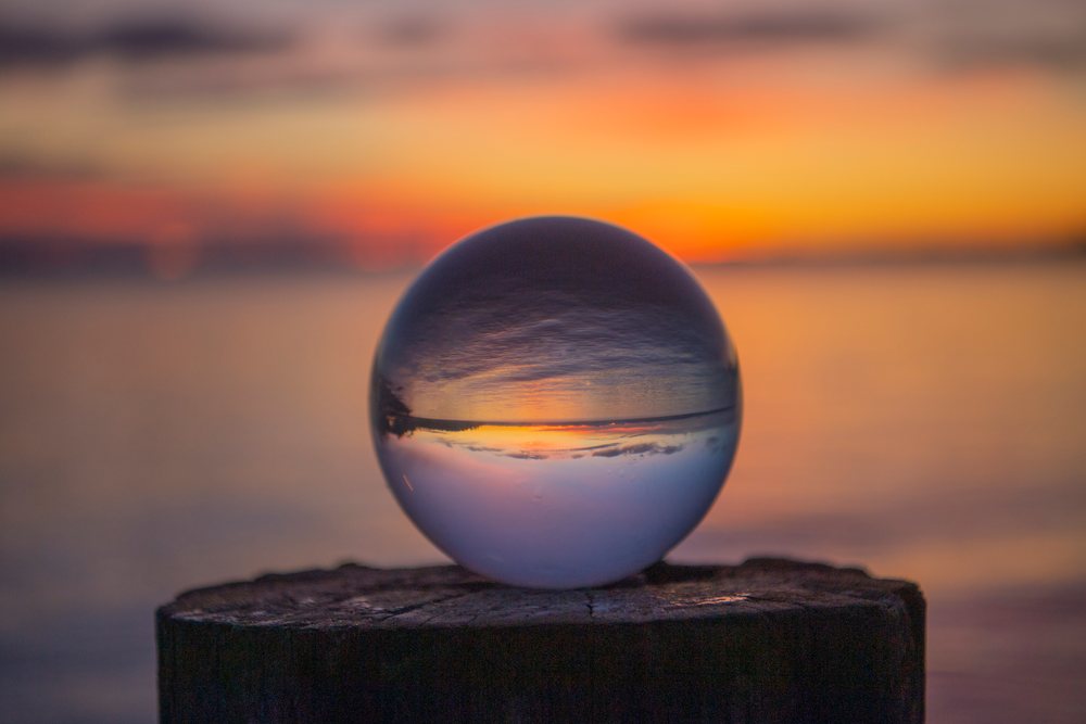 Crystal ball on a wooden post reflects the sunset over a calm lake, Washington, Norwegian Point, USA.