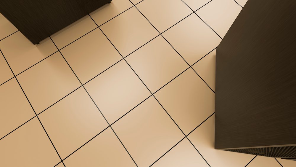 Beige square floor tiles with black grout arranged in a grid pattern on an indoor floor surface.