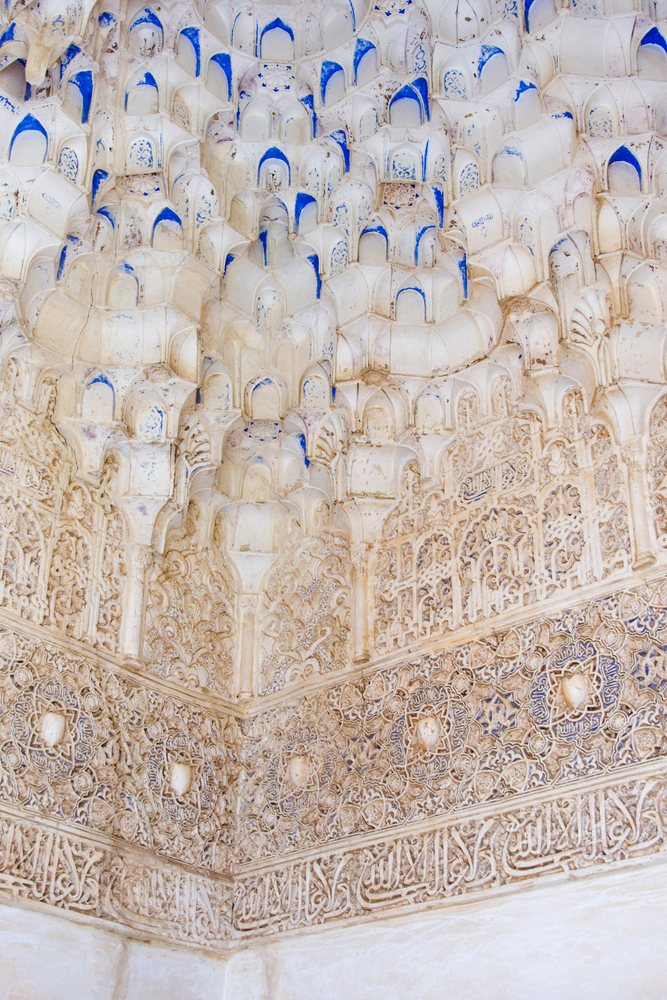 Intricate muqarnas and arabesque plasterwork adorn a corner interior wall of the Alhambra palace, Andalucia, Spain.