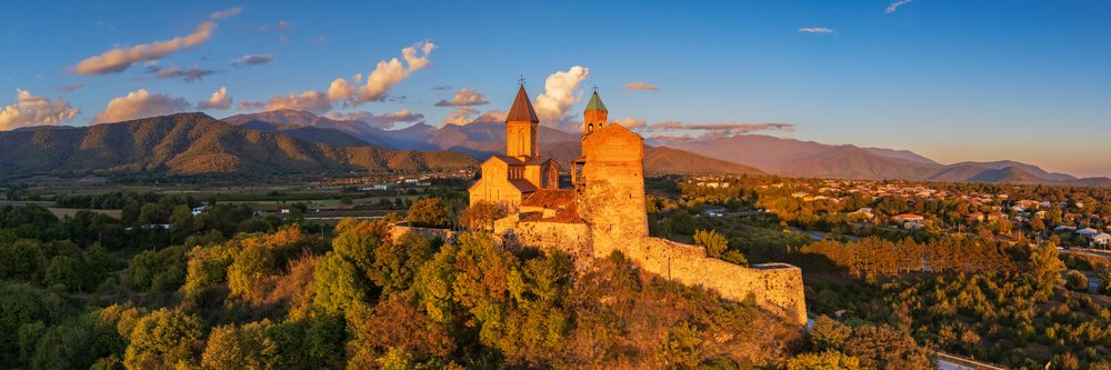 Historic Gremi Monastery sits atop a hill at Sunset, with mountains and clouds in the background, Sighnaghi, Georgia.