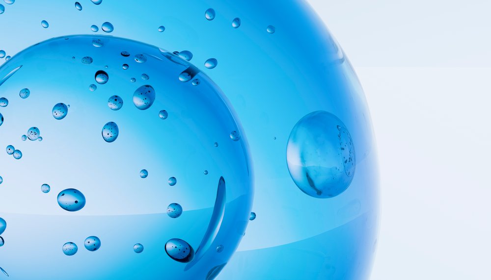 Close-up view of blue transparent bubbles of various sizes with small air droplets inside against a clean light background.