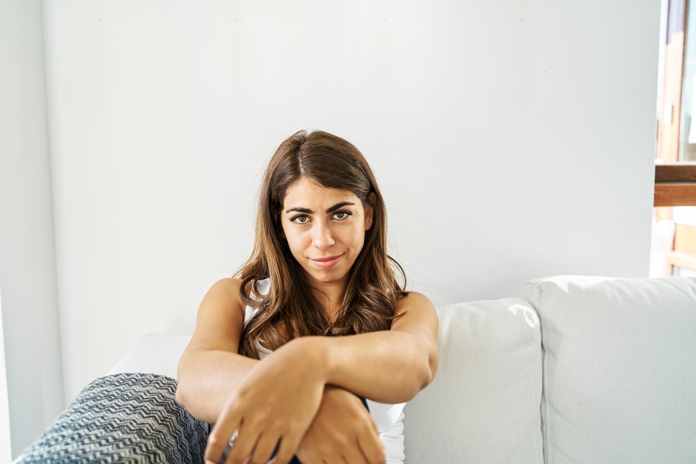 Young woman sitting comfortably on a white couch in a bright room