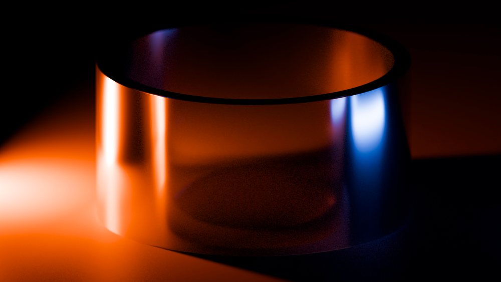 Reflective metal cylinder illuminated by orange and blue studio lights against a dark background.