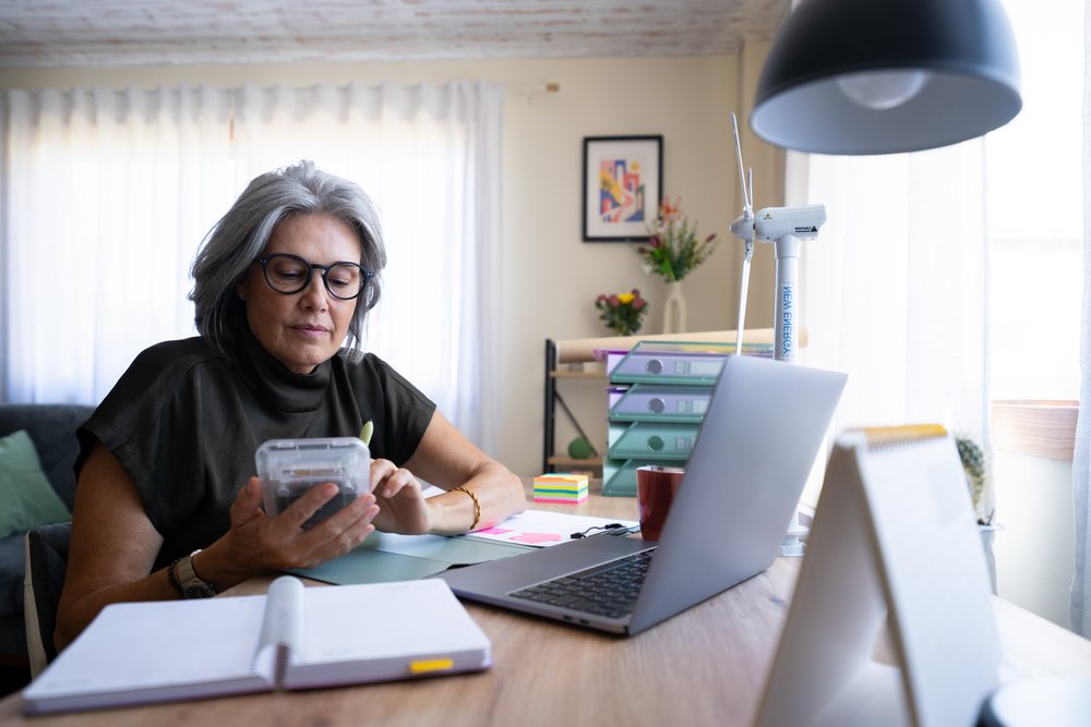 Woman working at desk with laptop and stationery in home office, Spain.