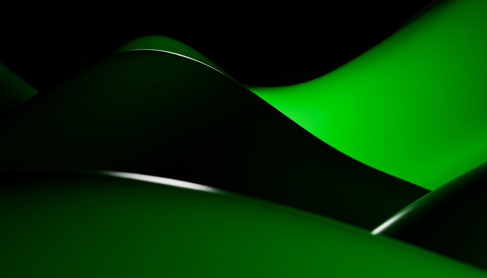 Close-up view of smooth green abstract curves with glossy surfaces and gradient lighting on a dark background.