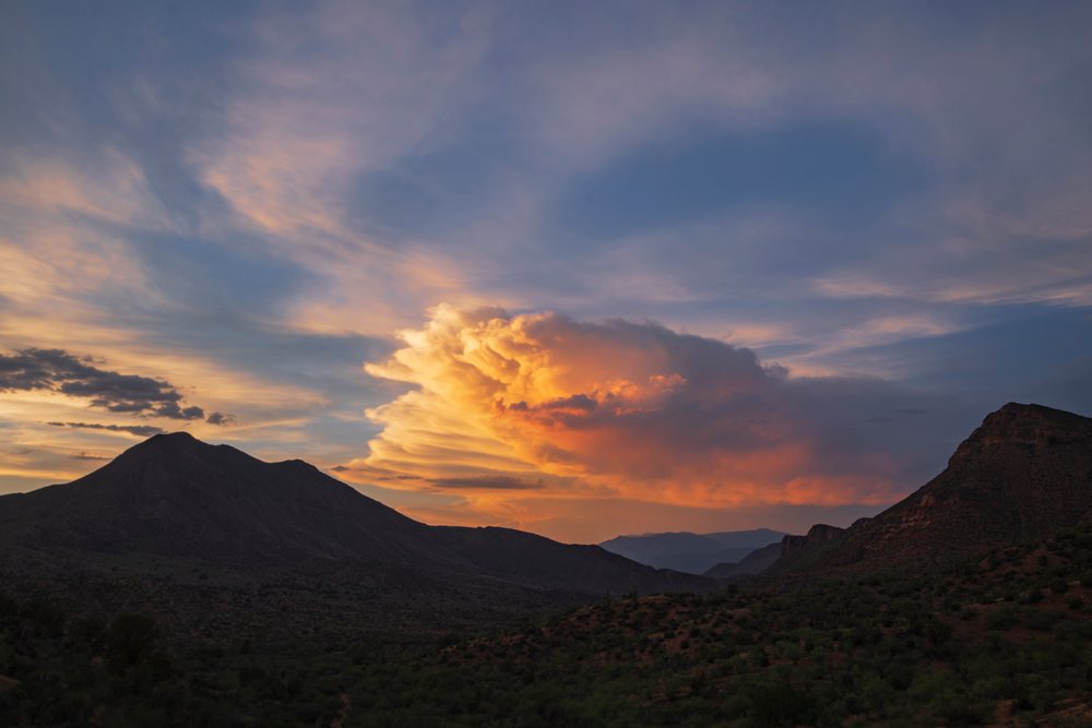 Thunderstorm cloud illuminated by Sunset over mountainous terrain with arid vegetation, Storm Chasing, Weather, Environment, Globe, Arizona, USA.