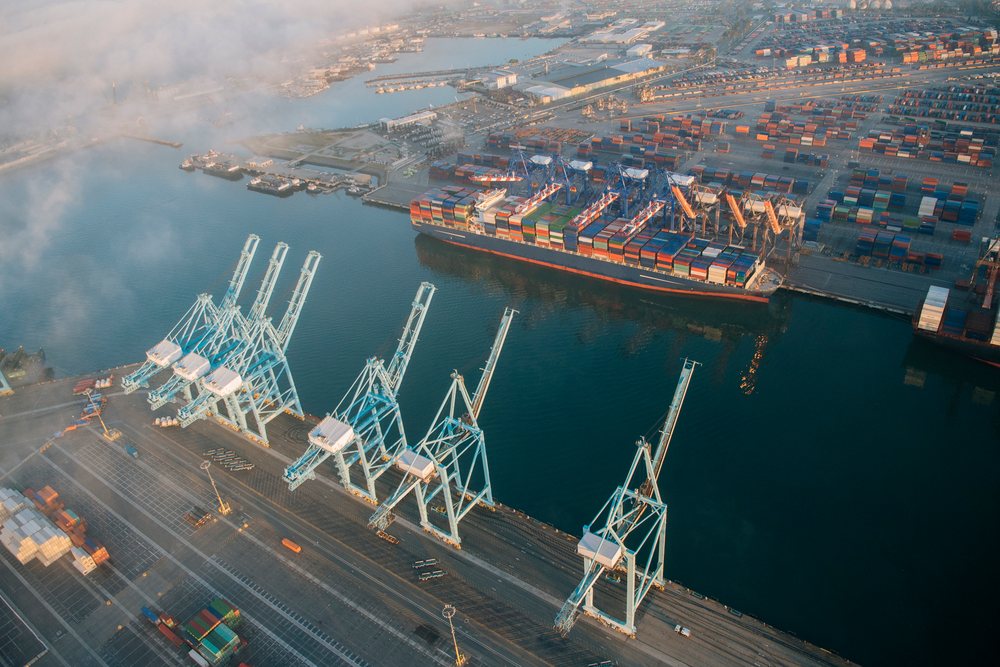Container ship loaded with cargo containers docked at a port with visible port cranes and container yard area, loted at the, Port of Long Beach, CA, USA.