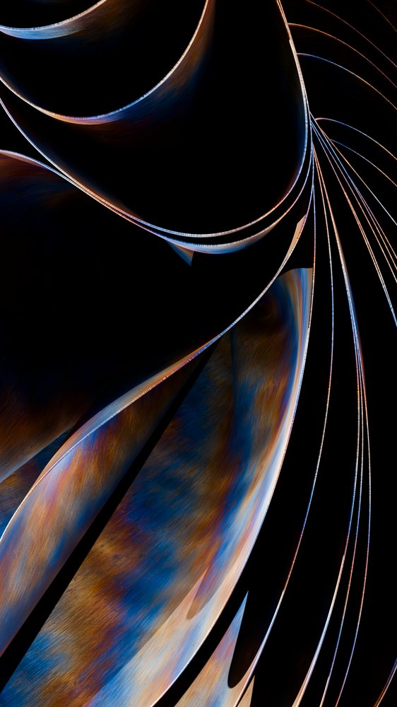 Curved metal abstract sculpture with colorful blue and rust shades on a black background.