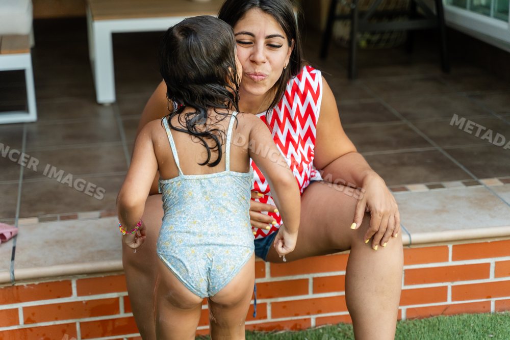 A young white girl kisses a woman sitting on a patio step