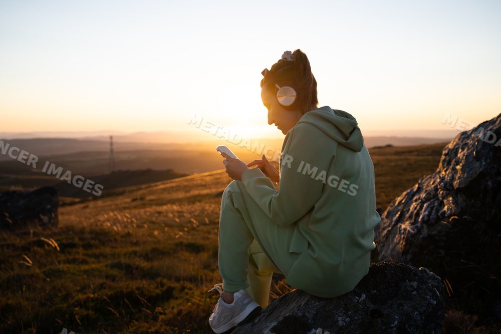 Young white woman listening to music on smartphone outdoors