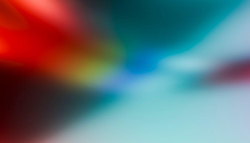 Abstract blurred background featuring vibrant red, blue, and green color gradients blending smoothly in a soft focus effect.