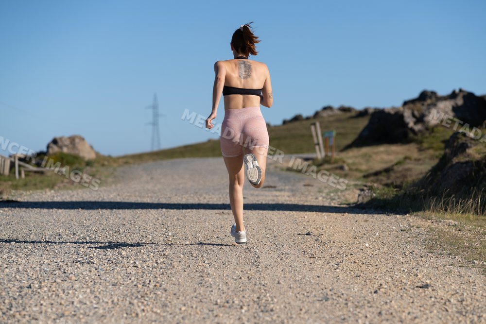 White Woman running on a gravel trail in an outdoor nature setting