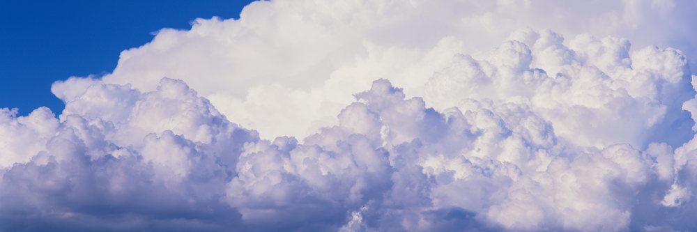 White cumulus clouds form a fluffy pattern in a vibrant blue sky on a clear day.