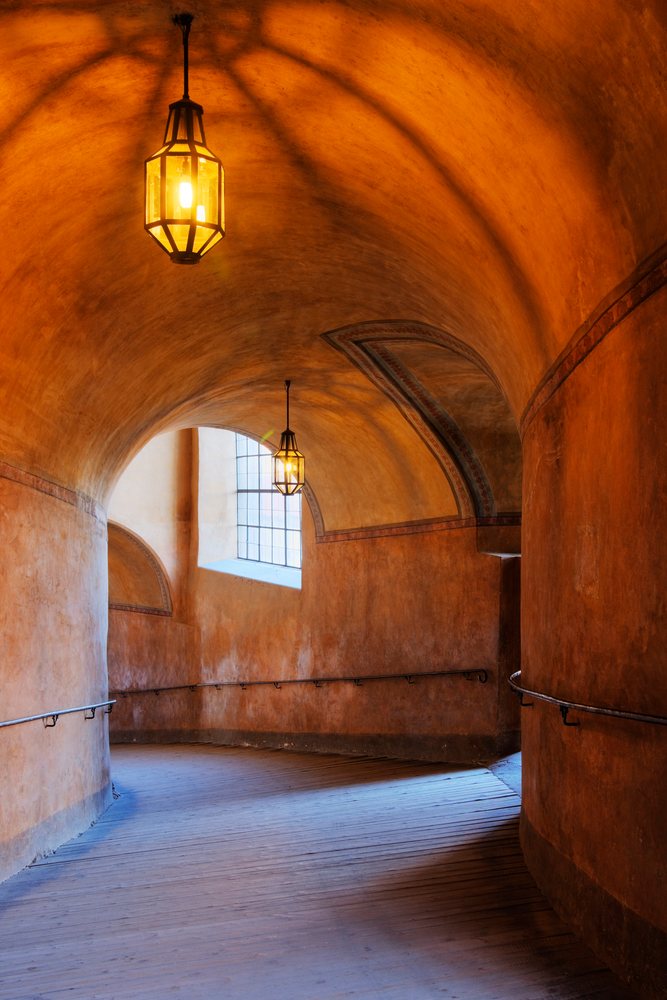 Curved arched hallway with wooden floor and orange walls inside Cesky Krumlov Castle, Bohemia, Czech Republic.