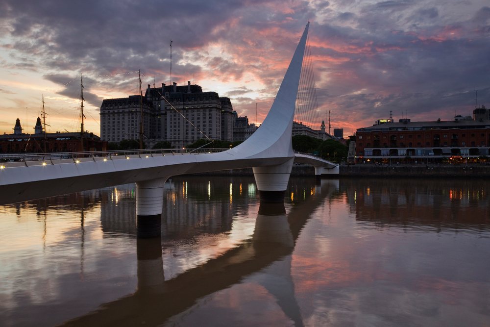 Puente de la Mujer, a white cable-stayed bridge, reflects on the river at sunset in the urban waterfront of, Buenos Aires, Argentina.