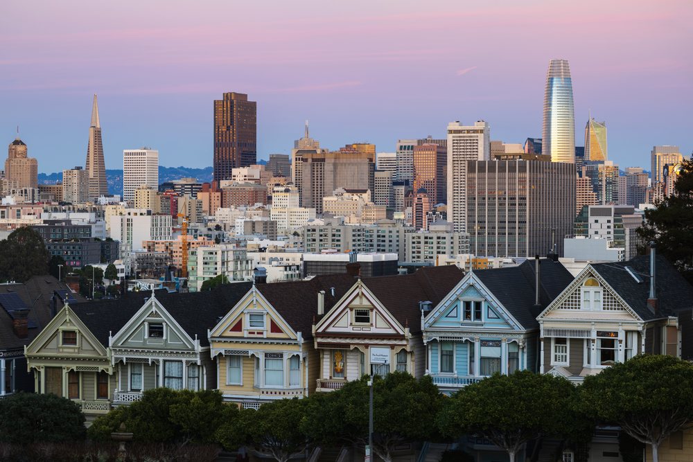 Twilight view of San Francisco's downtown Skyline with Victorian Painted Ladies houses and trees in the foreground under a pink-hued sky, City, Cityscapes, City Life, California, USA.