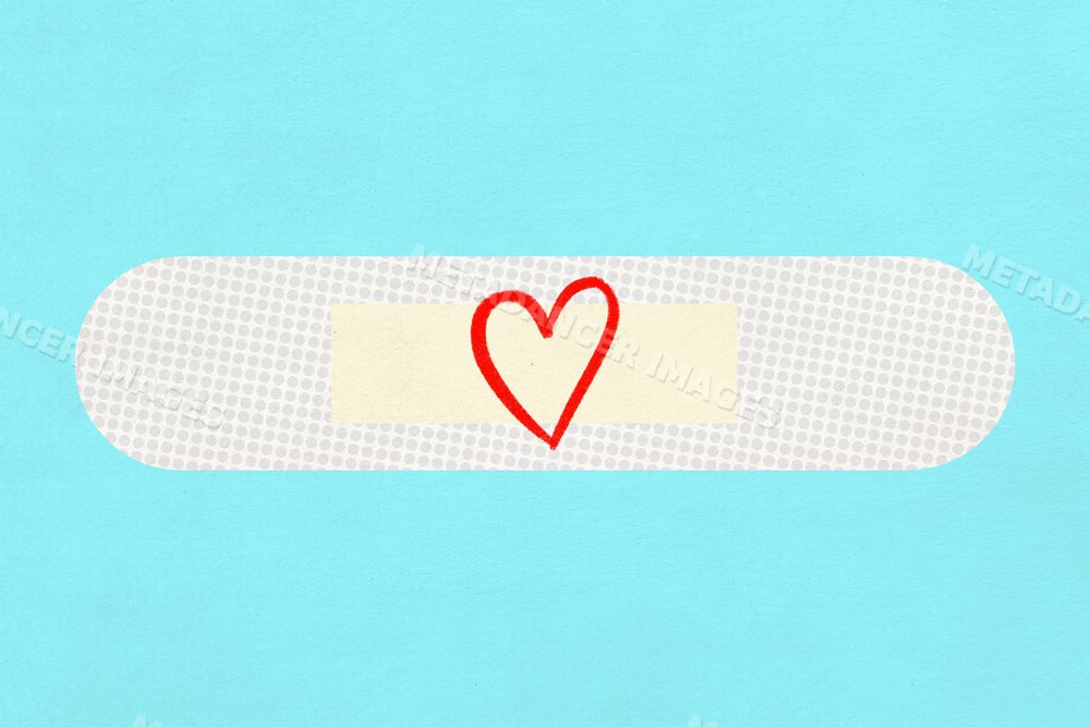 A white adhesive bandage with a red heart drawing on blue background