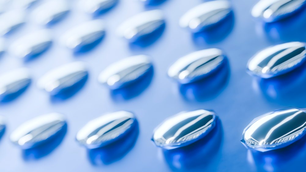 Close-up digital illustration showing a blister pack with transparent cavities holding blue capsule pills with high-gloss surfaces.